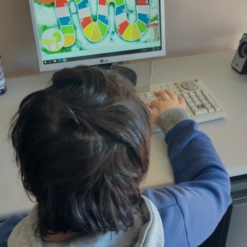Ένα άλλο παιδί κάθεται επίσης μπροστά από υπολογιστή σε σχολική αίθουσα και παίζει το παιχνίδι «Ταξιδιώτες»